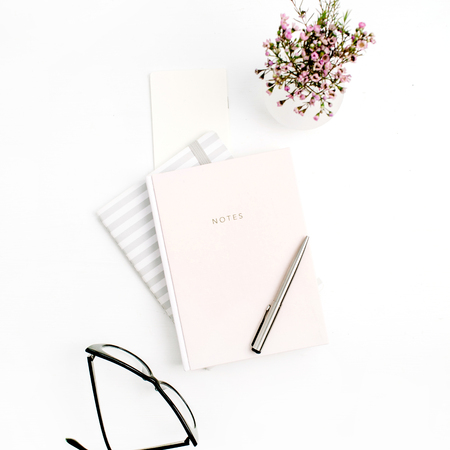 Female blog composition with notebook, glasses, pen and wildflowers on white background. Flat lay,...