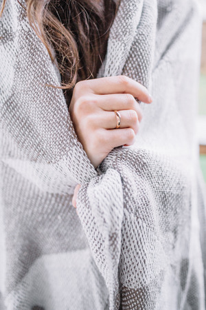 Young woman wrapped in grey blanket.の写真素材