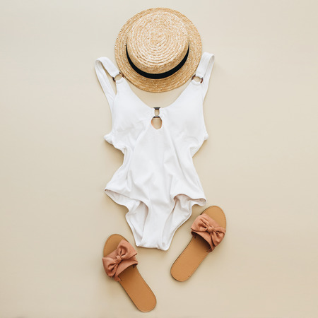 Flat lay summer fashion composition. Women's swimsuit, straw and slippers on pastel beige background. Flat lay, top view minimal beach concept.の写真素材
