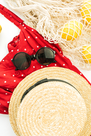 Summer female fashion composition. Red dress, straw, string bag, sunglasses and lemons. Flat lay, top view.の写真素材