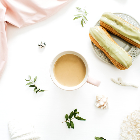 Coffee mug, pistachio cakes, pink blanket, string bag, seashells on white background. Flat lay, top...