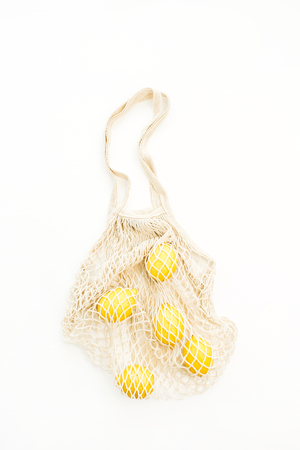 Fresh raw lemons in string bag. Flat lay, top view summer concept.の写真素材