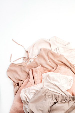 Female pale pastel pink clothes. Sweater, skirt, shirt on white background. Flat lay, top view minimal fashion concept.の写真素材