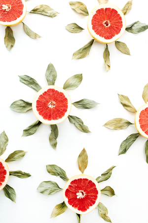 Sun symbol pattern made of sliced grapefruit and leaves. Flat lay, top view summer creative concept.の写真素材