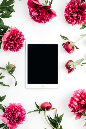 Tablet and pink peony flowers on white background. Flat lay, top view mock up.の写真素材