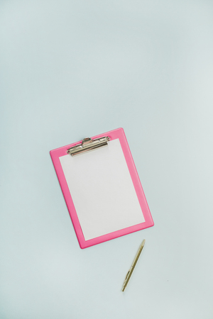 Minimalist flat lay office table desk with clipboard on blue background. Top view work concept mock up.の写真素材