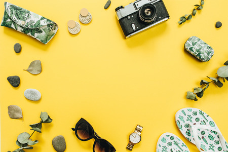 Flat lay summer travel fashion concept. Frame of slippers, retro camera, sunglasses, accessories on yellow background. Top view.の写真素材