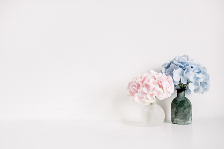 Pink and blue hydrangea flower bouquets on white background. Minimal interior design floral concept.