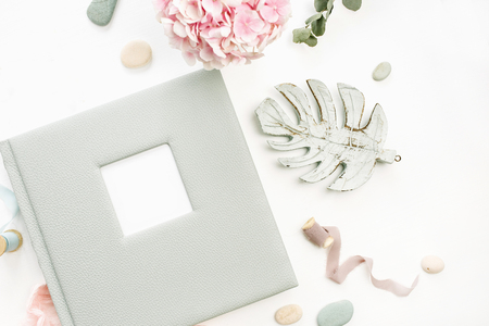 Composition with wedding or family photo album, hydrangea flower bouquet, eucalyptus branch, pastel pink blanket, monstera leaf decor on white background. Flat lay, top view.の写真素材