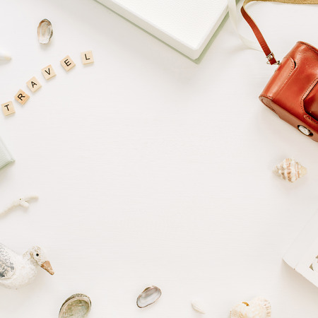 Frame border of travel styled composition with photo album, retro camera, bird sculpture on white background. Flat lay, top view traveler blog mock up.の写真素材