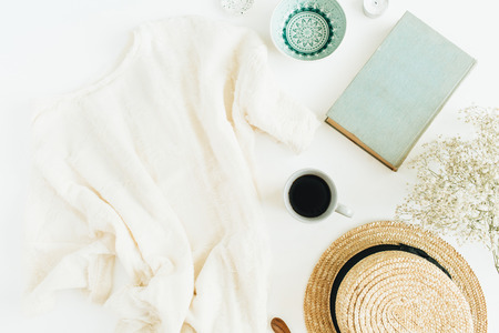 Home office desk with coffee, book, straw hat and blanket on white background. Flat lay, top view.の写真素材