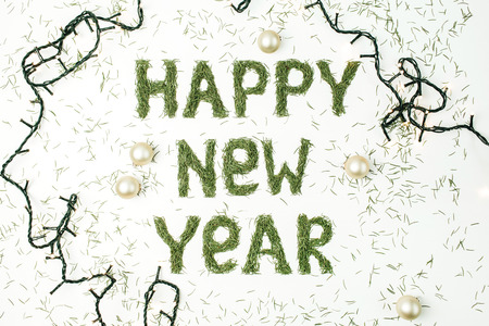 Quote HAPPY NEW YEAR made of conifer needles and decorations on white background. Flat lay, top view New Year composition.の写真素材