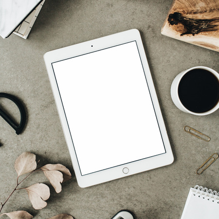 Flatlay of tablet with copy space screen mock up. Top view home office desk workspace decorated with eucalyptus, wooden board and stationery.の写真素材