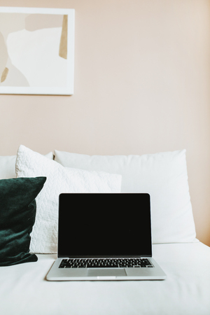 Minimal home office workspace. Laptop with mock up screen on bed with pillows. Blogger / freelancer business concept.の写真素材