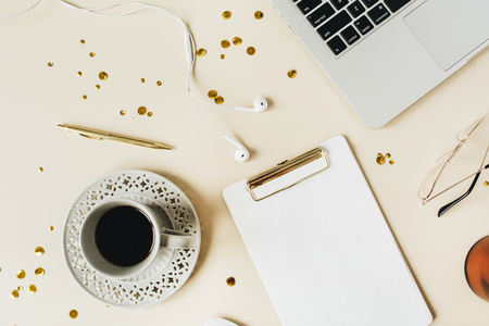 Minimalist home office desk workspace with clipboard, laptop, coffee, headphones on beige background. Flat lay, top view blog, social media, website hero header template.の写真素材