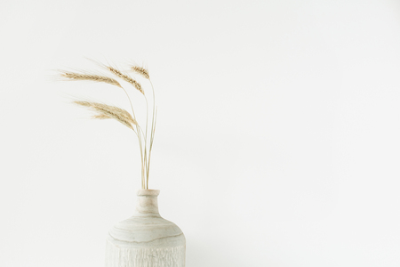 Wheat spikes bouquet in wooden vase on white background.の写真素材