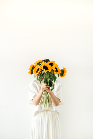 Young woman in white dress hold sunflowers bouquet on white background. Florist concept.の写真素材