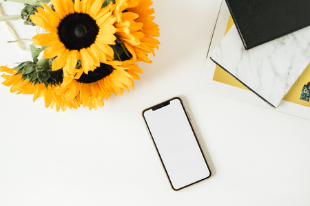 Phone template with copy space mockup screen and yellow sunflowers bouquet on white background. Flatlay, top view summer floral blog concept.の写真素材