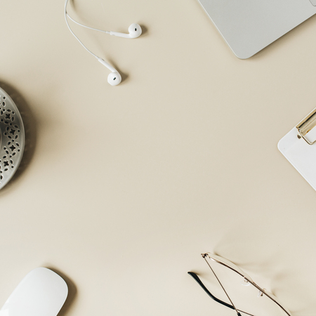 Round frame blank copy space mock up home office desk workspace with laptop, clipboard, headphones, coffee on beige background. Flat lay, top view modern minimalist blog hero header template.の写真素材