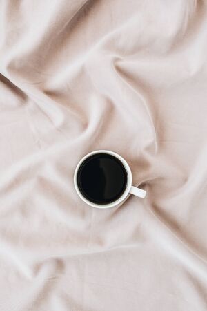 Flatlay of black coffee mug on pastel pink blanket. Minimal top view template.の写真素材