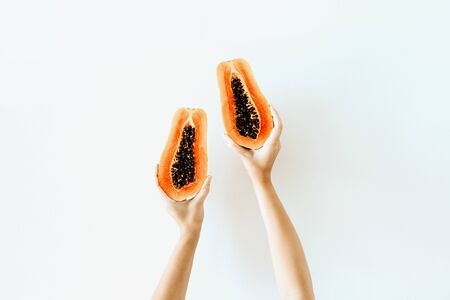 Summer and travel concept. Young woman's hands holding exotic tropical orange papaya fruit. Minimalistic seasonal vegetarian background. Front view.の写真素材