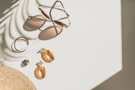 Fashion composition with women's accessories on white background. Earrings, sunglasses, bracelet, straw hat on white background. Flat lay, top view lifestyle blog concept.の写真素材