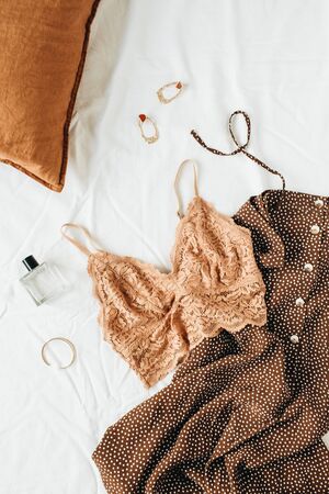 Fashion collage with trendy women's underwear and accessories: bra, dress, earrings, perfume, bracelet and pillow on white linen. Flat lay, top view minimal lifestyle beauty concept.の写真素材