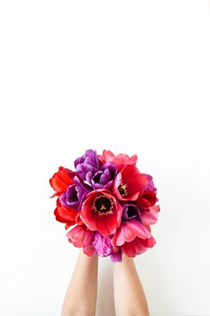 Tulip flowers bouquet in women's hands on white background. Flat lay, top view summer floral concept.の写真素材