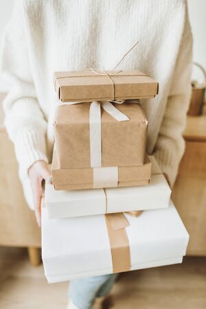 Young pretty woman hold Christmas / New Year gift boxes with bows. Traditional winter holidays gifts packaging creative concept. Flat lay, top view.の写真素材