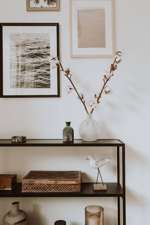 Modern scandinavian nordic living room with beautiful details such as black shelves, vases, frames, wooden caskets, cotton agains white wall. Scandi design interior concept.の写真素材
