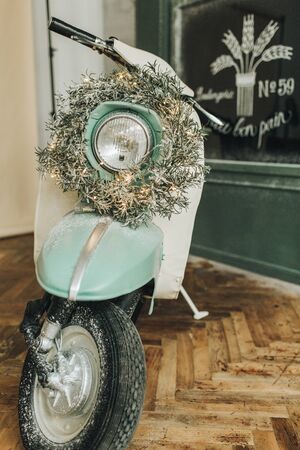 Christmas / New Year composition. Vintage retro old fashioned motorbike with christmas wreath and garland. Winter holidays concept.の写真素材