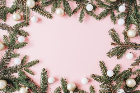 Christmas / New Year holiday composition. Mock up frame with blank copy space, fir needle branches, Christmas baubles on pink background. Flat lay, top view festive concept.の写真素材