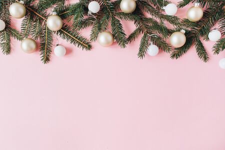 Christmas / New Year holiday composition. Hero header with blank copy space, fir needle branches, Christmas baubles on pink background. Flat lay, top view festive concept.の写真素材