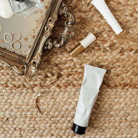 Fashion women accessories and cosmetics. Tray, perfume, concealer, lipstick, rings, earrings on straw background. Flat lay, top view fashion blogger concept for social media, website, blog.の写真素材