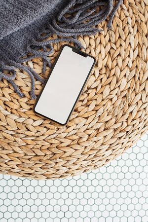 Blank screen smartphone with empty copy space mockup on rattan puff, plaid and mosaic tile. Flat lay, top view template for social media, website, blog, magazine.の写真素材