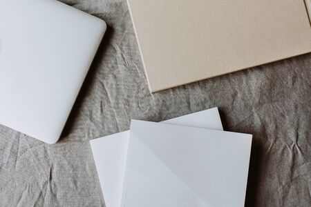 Minimal business background with laptop, paper sheet on grey washed linen table cloth. Flat lay, top...