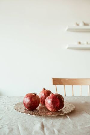 Three pomegranates on golden plate on beige tan table cloth.の写真素材