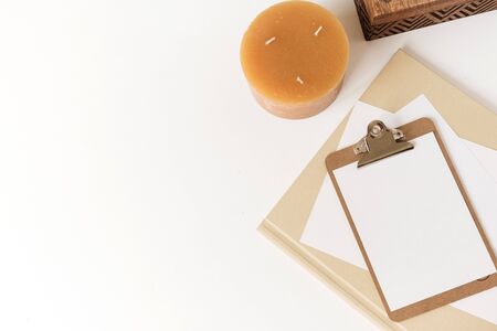 Blank paper sheet clipboard tablet pad with mock up copy space. Beautiful home office table desk workspace with wooden casket, candle, albums. Flat lay, top view art conceptの写真素材