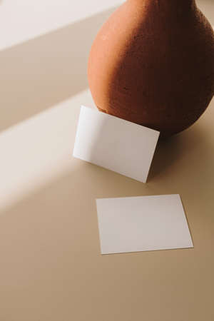 Blank paper sheet cards with mockup copy space and clay pot with dry wheat bouquet with sunlight...
