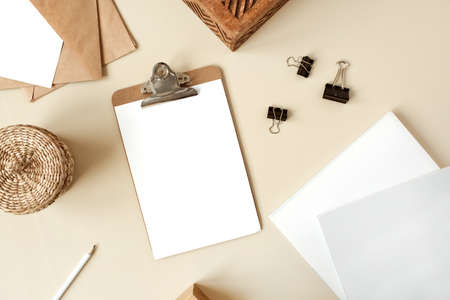 Clipboard tablet pad with blank paper sheet on beige table. Artist home office desk workspace with...