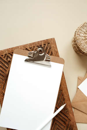 Clipboard tablet pad with blank paper sheet on beige table. Artist home office desk workspace with...