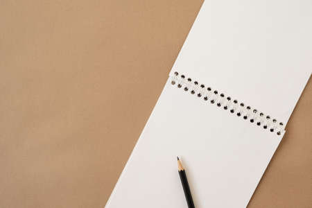 Closeup of spiral notebook and pencil on neutral beige pastel background. Blank paper sheet copy space mockup template. Empty space for text. Flatlay, top view.の写真素材