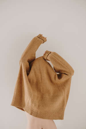 Young beautiful woman wear beige warm woolen sweater. Minimalist fashion lifestyle concept on white background.の写真素材