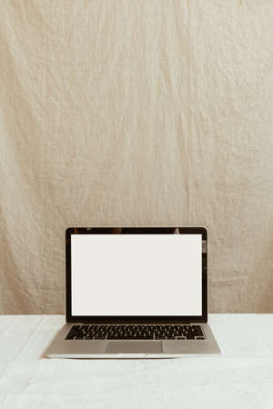 Front view blank screen laptop computer against pastel beige linen wall. Copy space mockup template.の写真素材