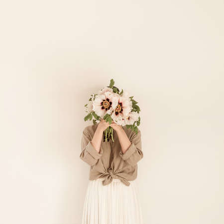 Young beautiful woman with white peonies flowers bouquet agains white wall.の写真素材