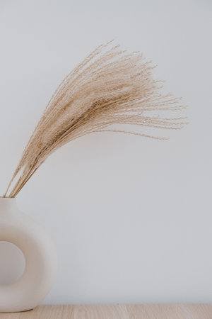 Modern hygge interior design decoration. Pampas grass / reed on wooden tablet against white...