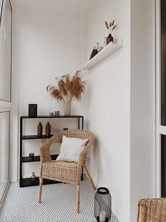 Beautiful white loggia in scandinavian style with rattan chairs, white pillow, black shelf, vases, pampas grass, candles. Nordic, higgle concept.の写真素材