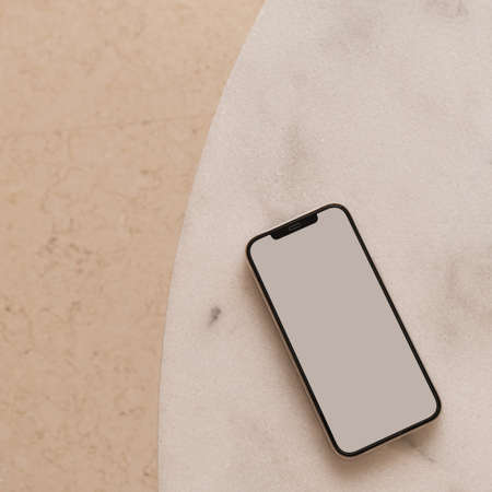 Blank screen smart phone on marble table. Flat lay, top view. Copy space mockup template.の写真素材