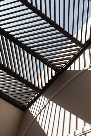 Modern east style building with beige walls and rail sunlight shadows on walls. Aesthetic abstract...