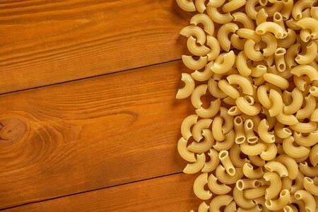 Uncooked pasta on a wooden background, copy space